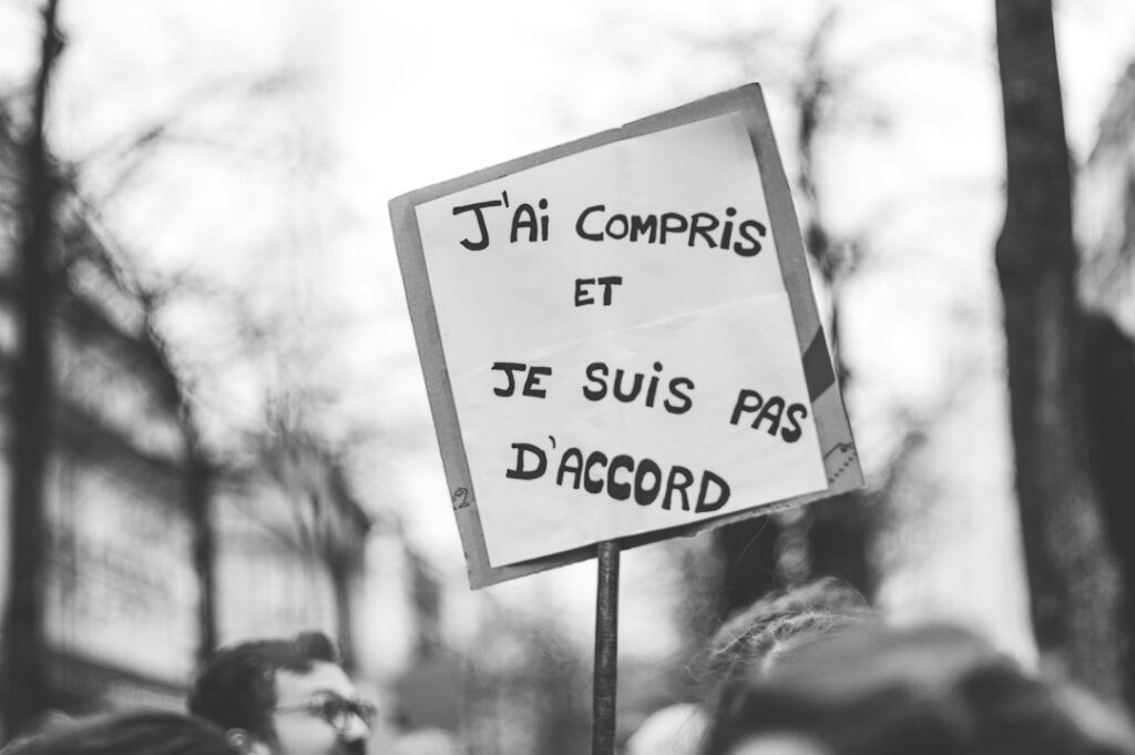 Protest sign with French text held high at an outdoor demonstration.